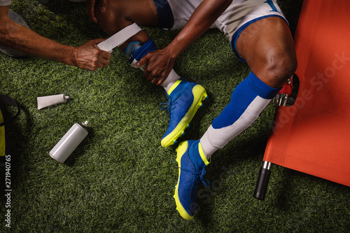 Fototapeta Naklejka Na Ścianę i Meble -  Soccer player injured knee during the game. Sport Doctors provide first aid to player on a professional football field. Close up