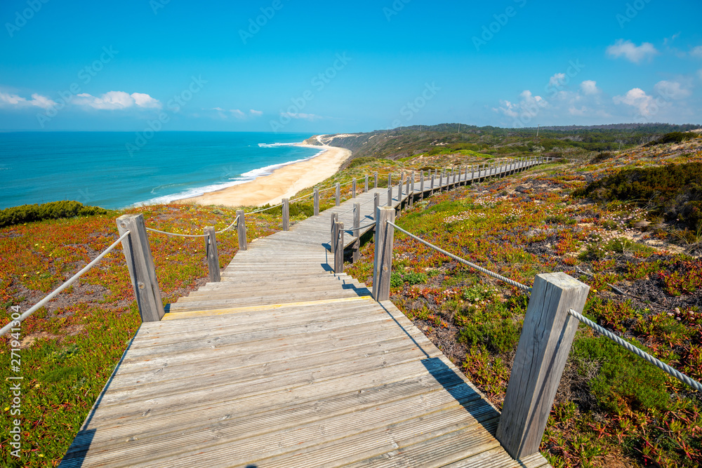Fototapeta premium The wooden stairway at the rocky seashore on a sunny day. Polvoeira the beach. Pataias, Portugal, Europe