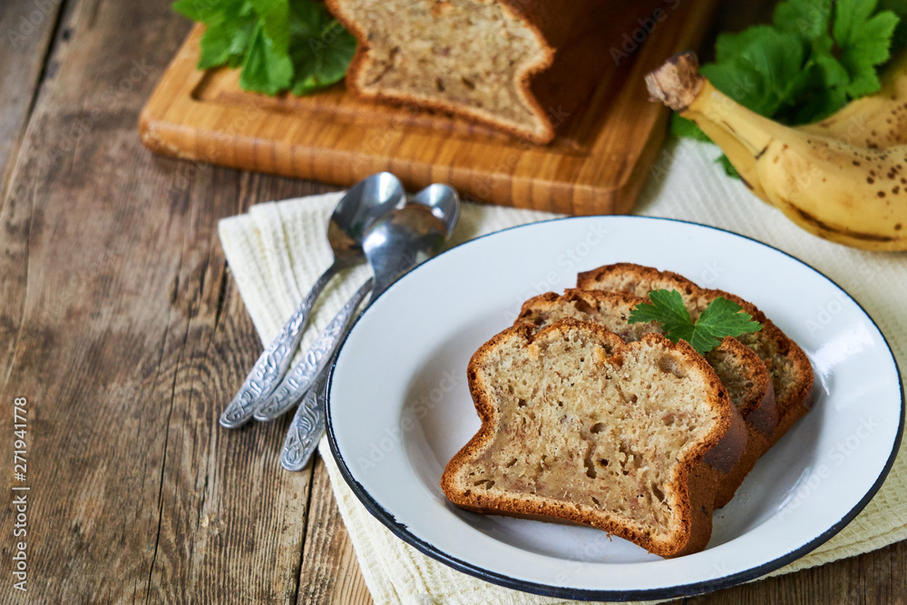 Slices of homemade banana bread in a white plate on a wooden table Slices of homemade banana bread in a white plate on a wooden table