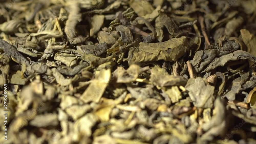 SLOW MOTION: Tea leaves fall on a pile of a green tea - Macro shot. SLOW MOTION: Tea leaves fall on a pile of a green tea - Macro shot.