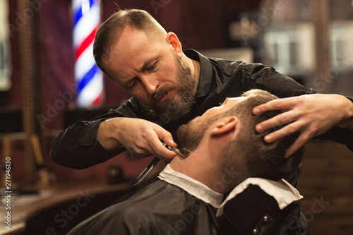Obraz na plátně Siew form side of careful male master in process of working in barbershop