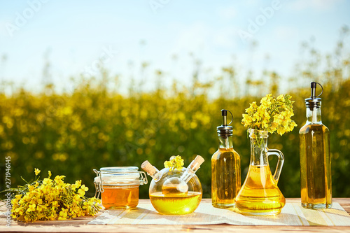 Rapeseed oil bottles (canola) on background rape field