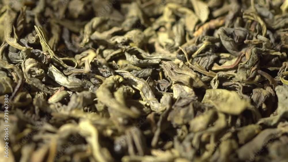SLOW MOTION: Tea leaves fall on a pile of a green tea - Macro shot. SLOW MOTION: Tea leaves fall on a pile of a green tea - Macro shot.
