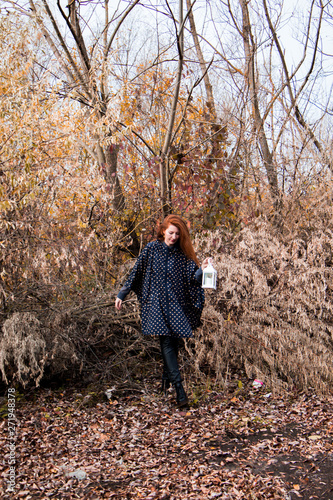 young redhead woman with white lamp in the hand in autumn park