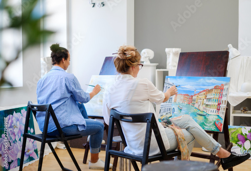 Creative painter and her protege working in a studio