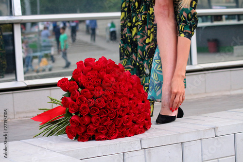 girl in a green dress with a bouquet of red roses at the mirror wall