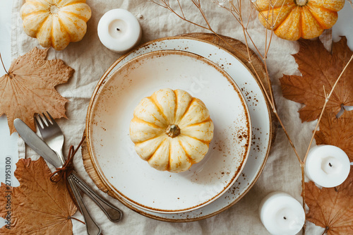 Top view on a decorated table setting for Thanksgiving dinner. Autumn ornate, white pumpkin on ceramic plates. photo