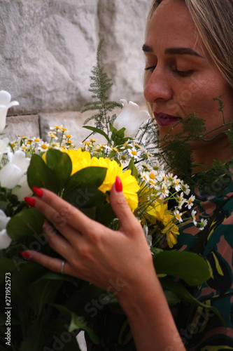 a girl in a green dress with a bouquet of yellow flowers at the concrete wall
