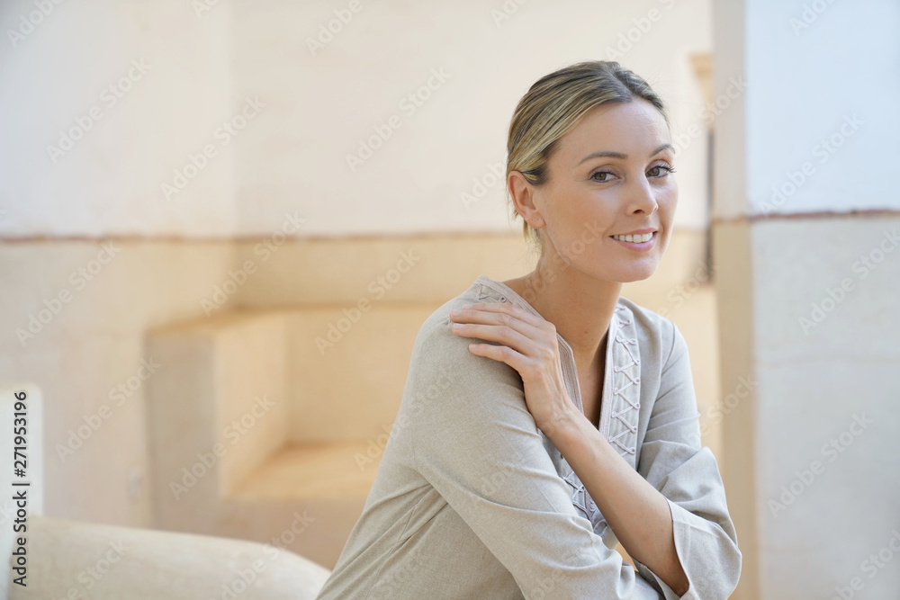 Stunning woman in soft neutral tones sitting in Moroccan villa smiling at camera Stunning woman in soft neutral tones sitting in Moroccan villa smiling at camera
