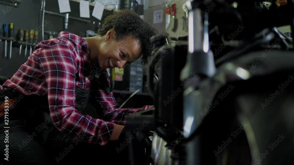African american woman mechanic repairing a motorcycle in a workshop African american woman mechanic repairing a motorcycle in a workshop