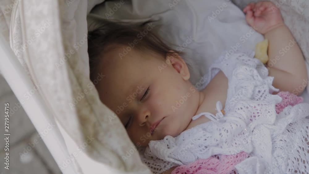Beautiful little girl sleeping in a baby carriage on the street. Beautiful little girl sleeping in a baby carriage on the street.