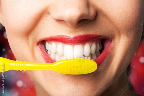 Female brushing teeth with yellow brush, close up