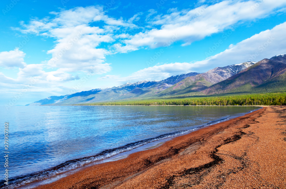 Baikal Lake. Sunny morning on the sandy beach of the Barguzinsky Gulf. View of the snowy peaks of the Holy Nose Peninsula (Svjatoj Nos). Summer landscape. Natural background