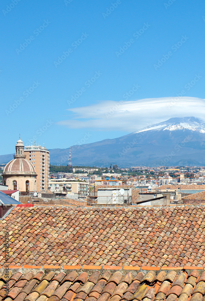 Vertical picture capturing beautiful cityscape of Catania, Sicily, Italy with dominant cupola of Cathedral of Saint Agatha. Majestic Mount Etna volcano in background