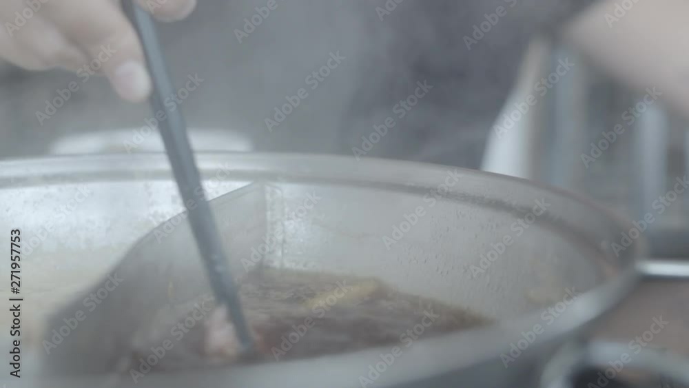 Asian woman eating hot pot in japanese restaurant, young female holding sliced beef meat by chopsticks eat shabu in lunch time. Lifestyle women eating food concept. Slow motion shot. Asian woman eating hot pot in japanese restaurant, young female holding sliced beef meat by chopsticks eat shabu in lunch time. Lifestyle women eating food concept. Slow motion shot.