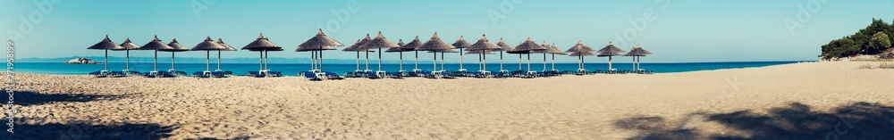 Panorama Beach Halkidiki with straw parasols and rock on a horizon. Selective focus