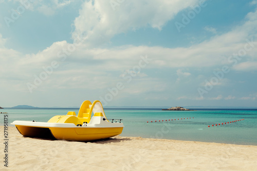 Fototapeta Naklejka Na Ścianę i Meble -  Yellow pedal boats on a turquoise beach in Greece and lines with red buoys Selective focus