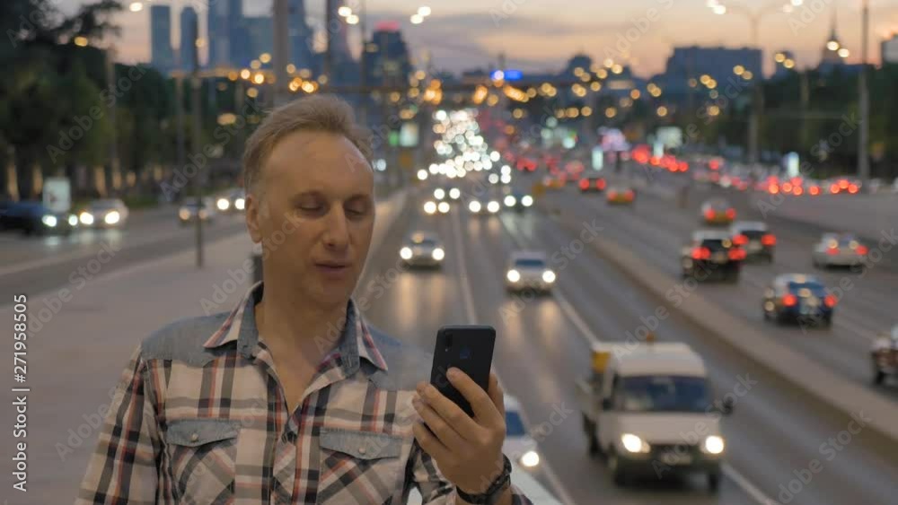 man makes selfie against wide street in evening city man makes selfie against wide street in evening city