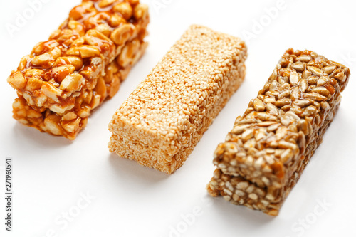 Grain granola bar with peanuts, sesame and seeds in a row on a white background. Top view Three assorted bars, isolate