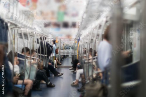 In the morning, many people, both men and women are standing and sitting on the subway who are travelling to work. In the city of Tokyo Japan photo