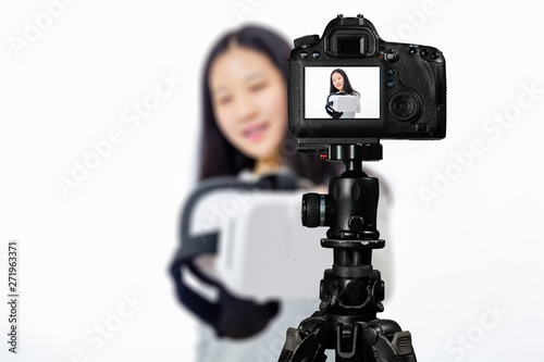 Focus on live view on camera on tripod, teenage girl with blurred scene in background. Teenage vlogger livestreaming show concept