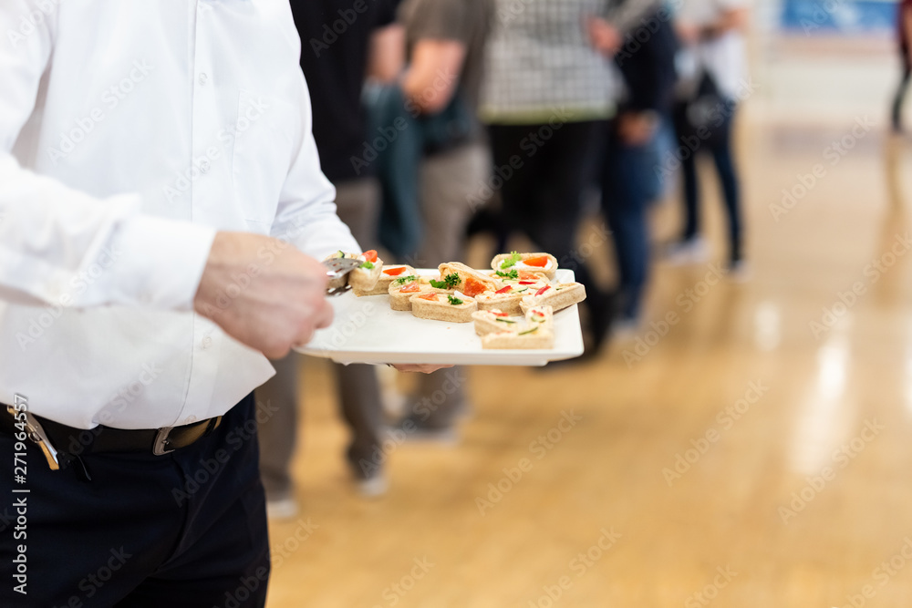 Waiter carrying plates with canapes on some festive event, party or wedding reception.