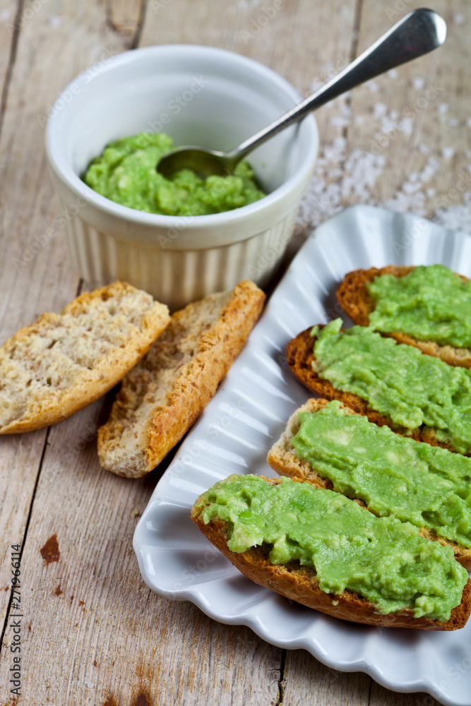 Croutons with avocado guacamole on white plate closeup on rustic wooden table. Croutons with avocado guacamole on white plate closeup on rustic wooden table.