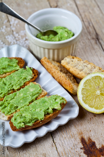 Toasts with avocado guacamole on white plate closeup on rustic wooden table. Diet breakfast.