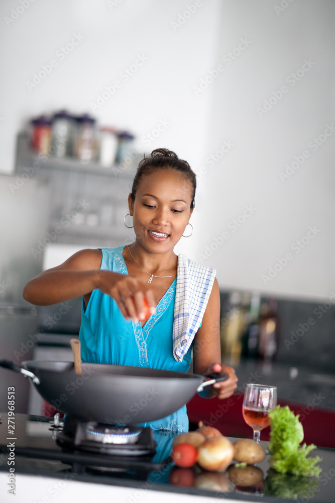 housewife in kitchen squeezes tomato in meal