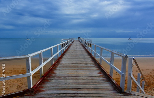 Great views of Hervey Bay from the wooden Torquay jetty. The pier is also a popular fishing spot at all tides. Gushing sea on a cloudy day. Horizontal view of dramatic overcast sky and sea. © katacarix