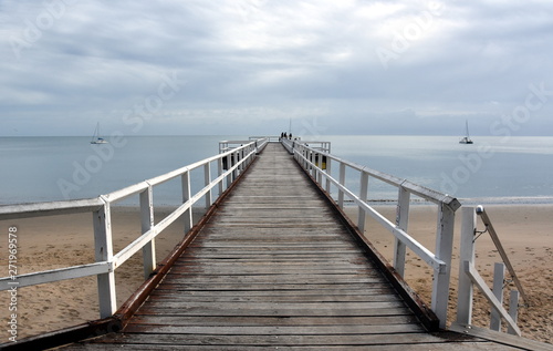Great views of Hervey Bay from the wooden Torquay jetty. The pier is also a popular fishing spot at all tides. Gushing sea on a cloudy day. Horizontal view of dramatic overcast sky and sea. © katacarix