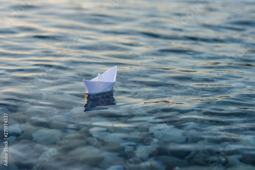 Fotografie Origami paper boat sails on the surface of water