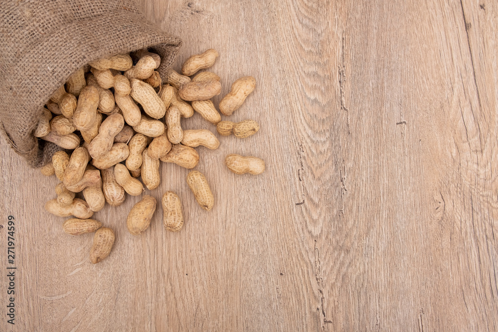 Top view of overturned scattered peanuts, poured roasted peanuts on wooden table, top view Top view of overturned scattered peanuts, poured roasted peanuts on wooden table, top view