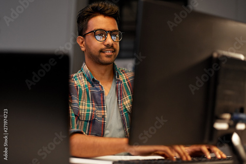 deadline, technology and people concept - close up of creative man in glasses working at night office and thinking