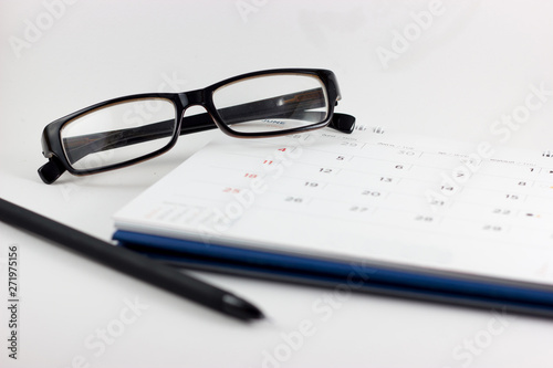 Calendar, eyeglasses and pen on white background. Eyeglasses focus