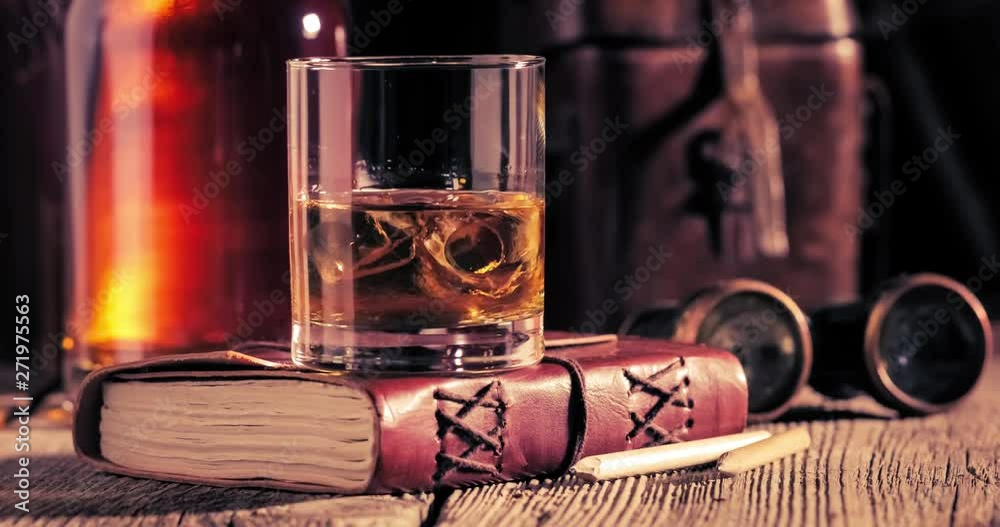 Melting and spinning ice and whisky in the glass on old diary