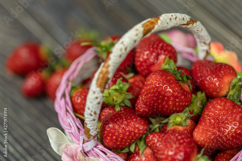 Strawberries in a small basket on the wooden table