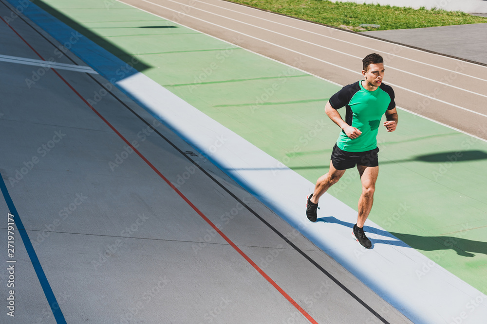 Fototapeta premium full length view of mixed race sportsman running at stadium