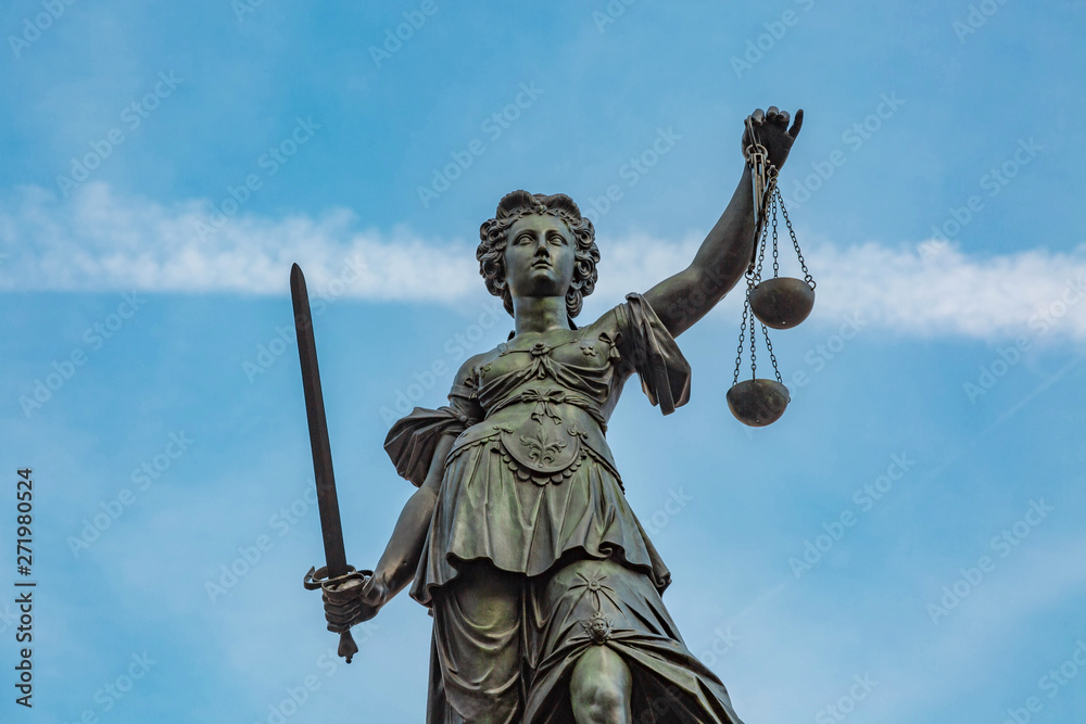 Justitia Figur hält die Waage der Gerechtigkeit hoch Justitia Figur hält die Waage der Gerechtigkeit hoch