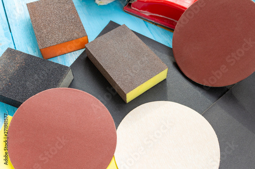 Abrasives, sanding paper sponges and sanding wheel respirator composition on the blue wooden background close up