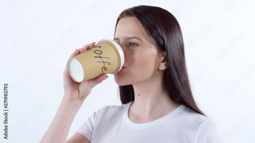 Portrait of young woman standing isolated on white background and drinking coffee from disposable cup Portrait of young woman standing isolated on white background and drinking coffee from disposable cup
