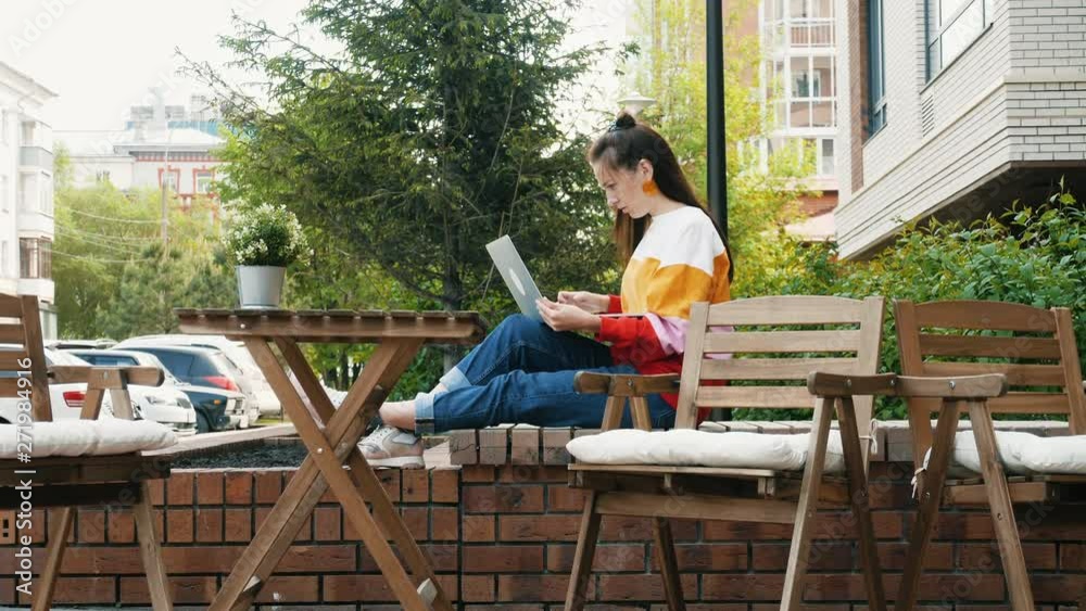 Young female freelancer with laptop in outdoor cafe Young female freelancer with laptop in outdoor cafe