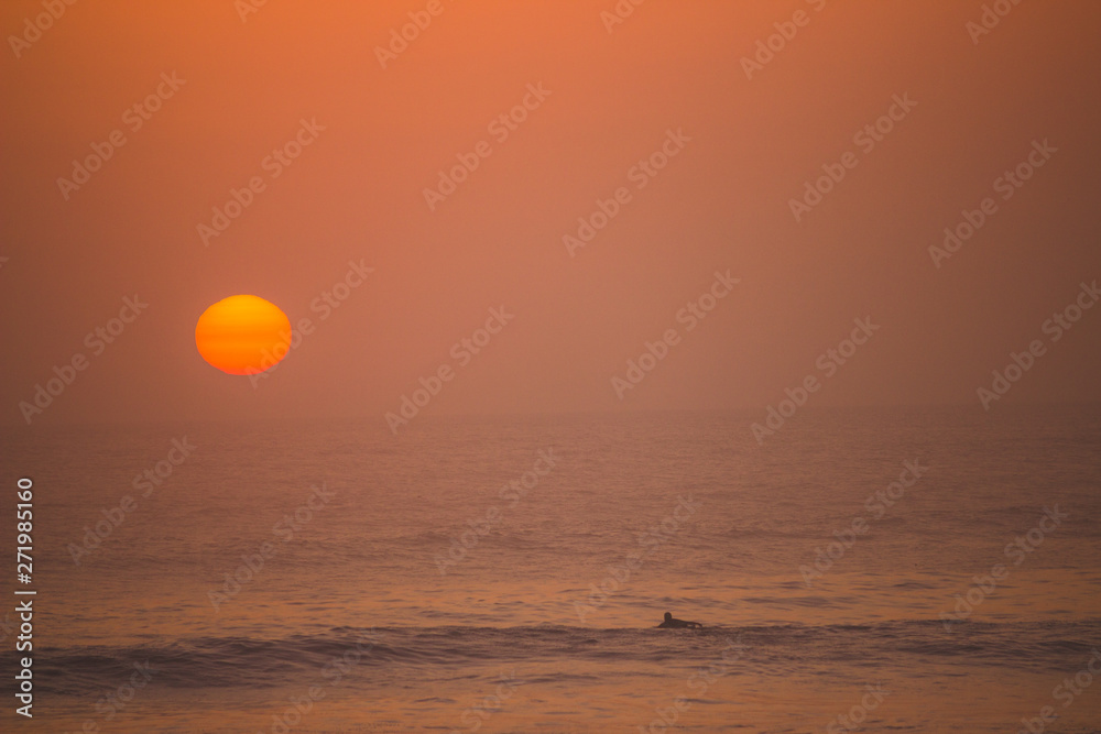 sunset over the ocean with a surfer in huanchaco, peru