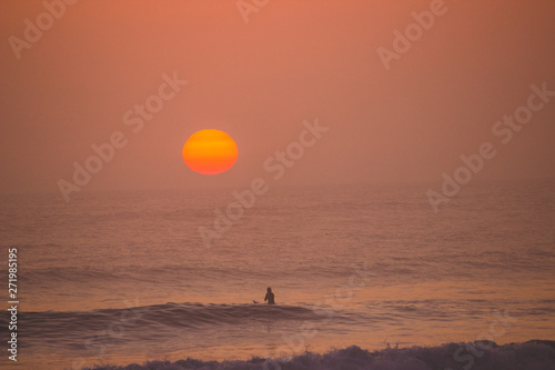 sunset over the ocean with a surfer in huanchaco, peru photo