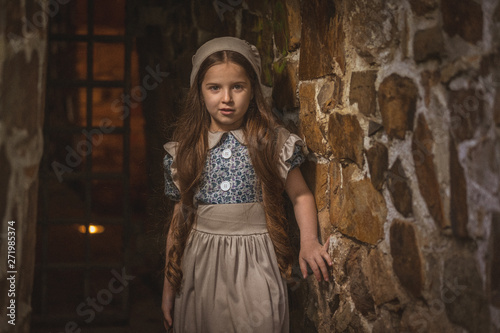 Frightened girl in the dungeons of an ancient castle. Stylization. Vintage toning.