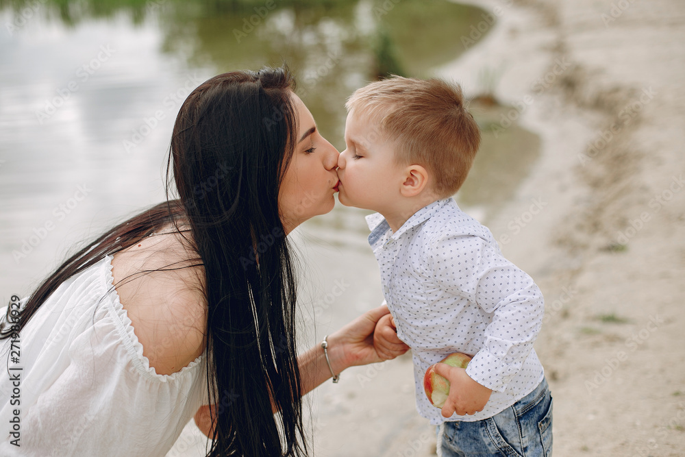 Obraz premium Family walking near water. Mother in a white dress. Cute little boy