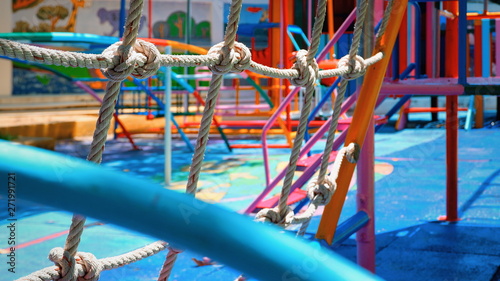 Focus on rope mesh and blurred colorful outdoor play equipments in playground area at kindergarten school