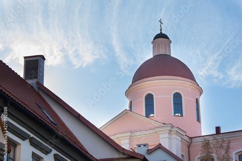 Pink tower of the cathedral in Vilnius, Lithuania. Dome against blue sky in a bright day light. Orthodox church and architecture building with the cross on the roof. Christian religious traditions.