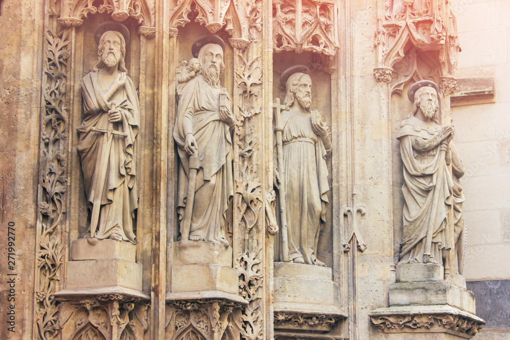 Various statues of saints on the ancient historic facade of the French cathedral. Religious sculptures and statues. Heritage and art of Paris. Bas-relief of the church.
