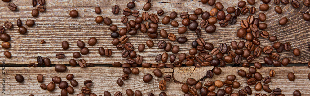 panoramic shot of wooden weathered table with scattered fresh roasted coffee beans panoramic shot of wooden weathered table with scattered fresh roasted coffee beans